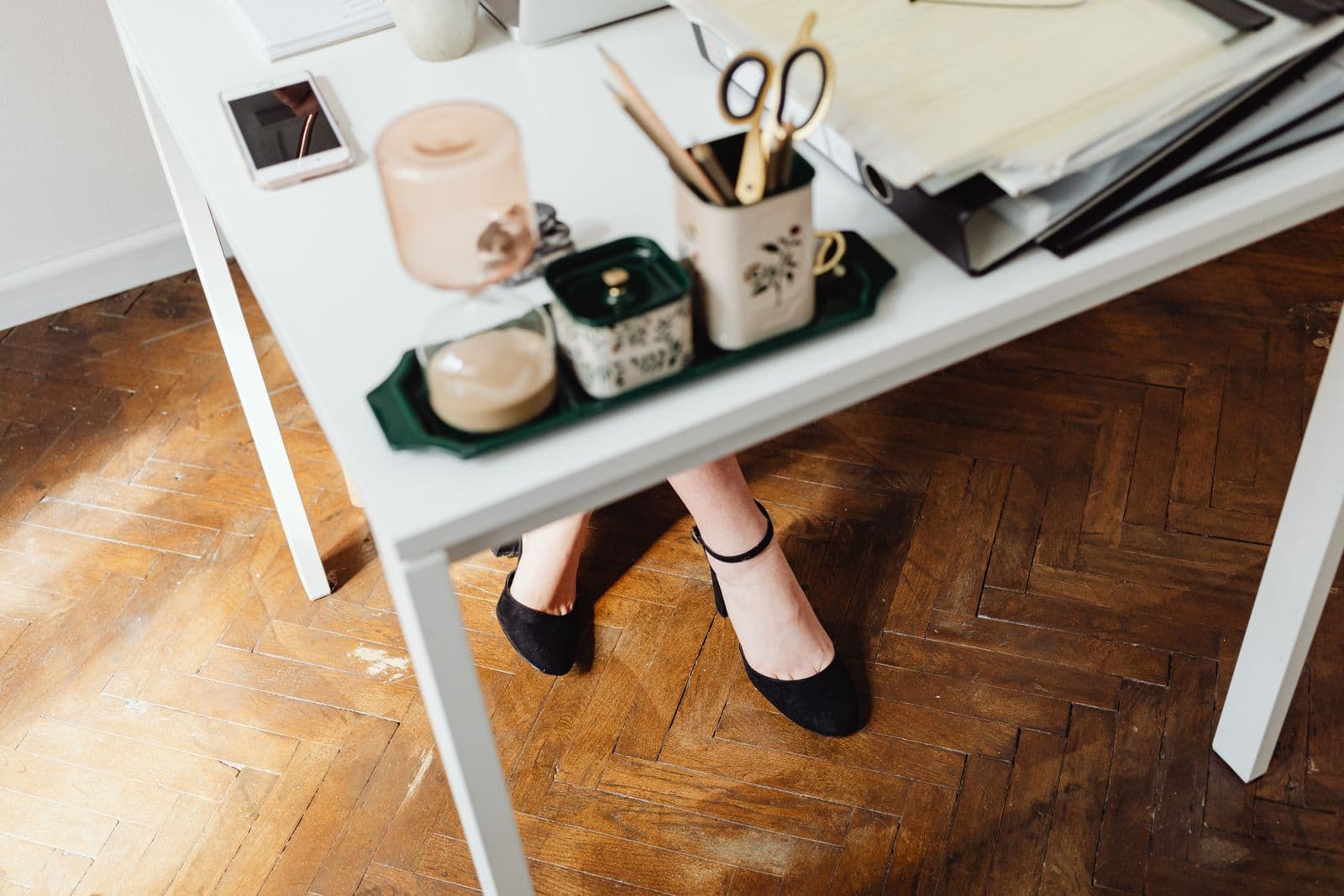 A person's feet resting on the floor under a white desk