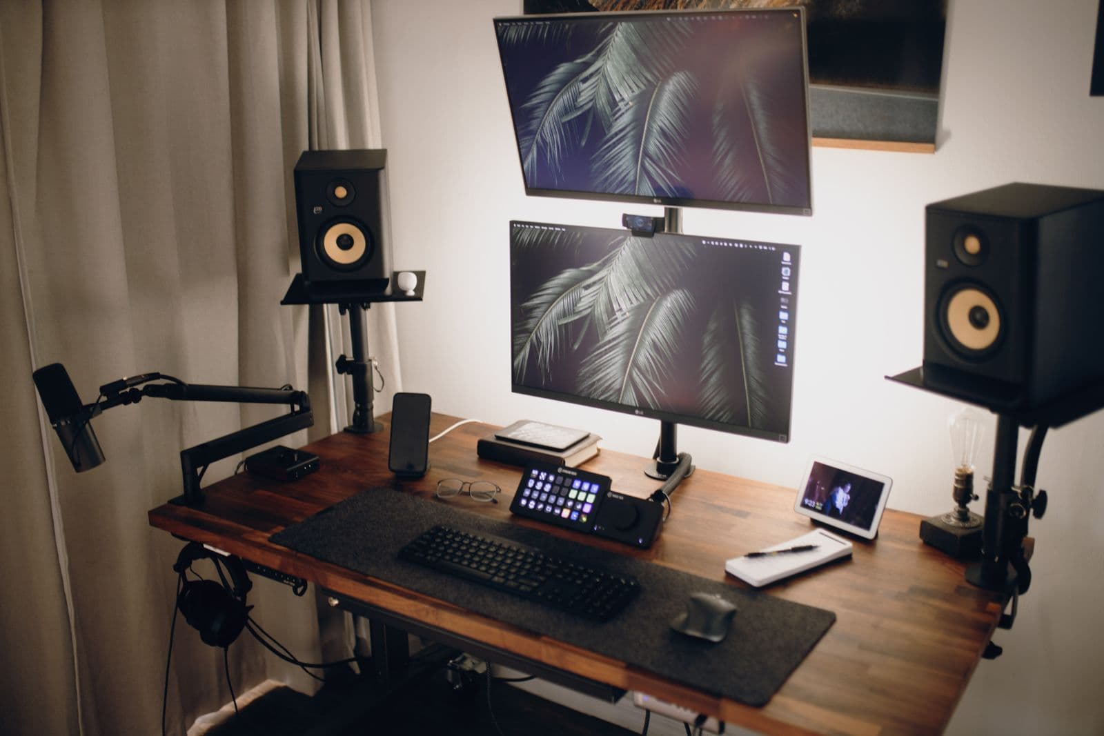 Two monitors mounted on arms above a wooden desk