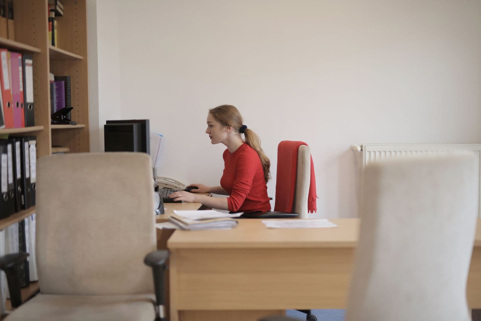 A person working in profile at a desk beside a window