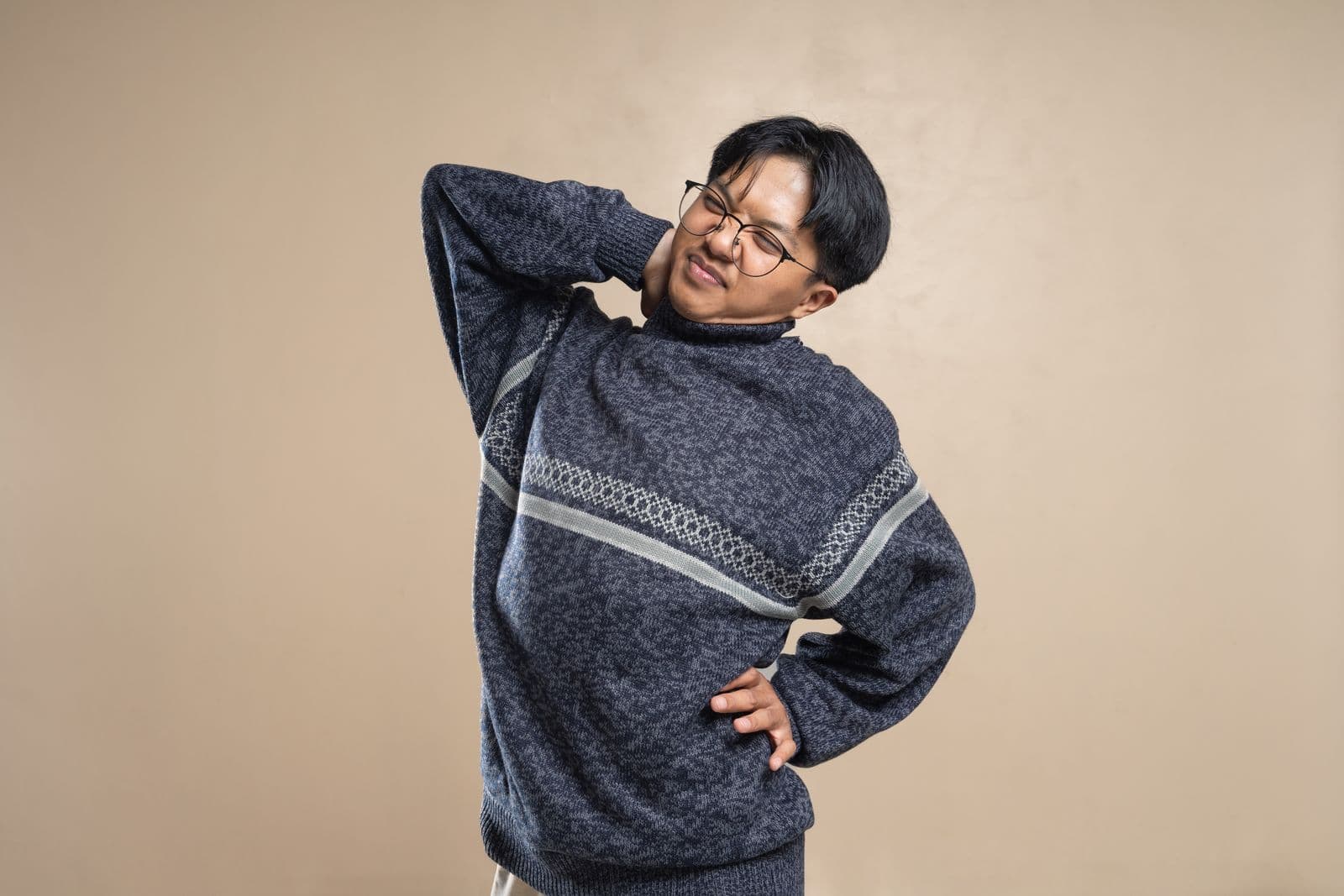 A man in a sweater stretching his shoulders indoors