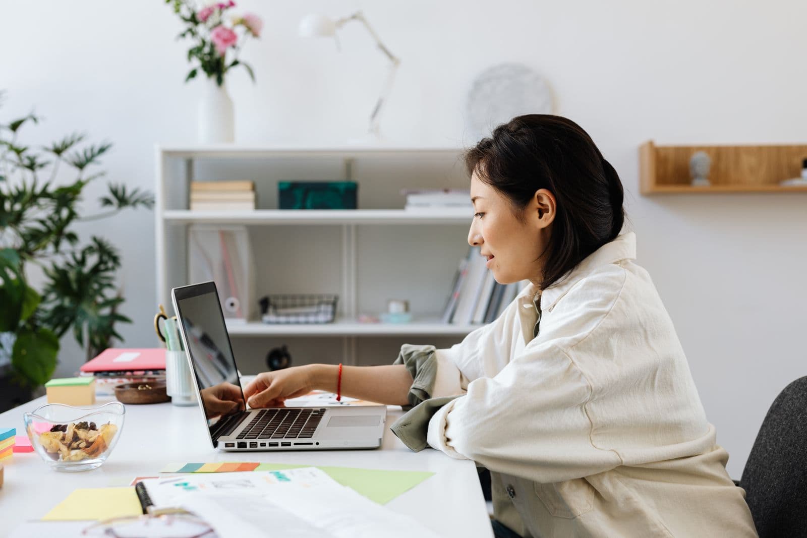 A woman working at a laptop in a plant-filled home office
