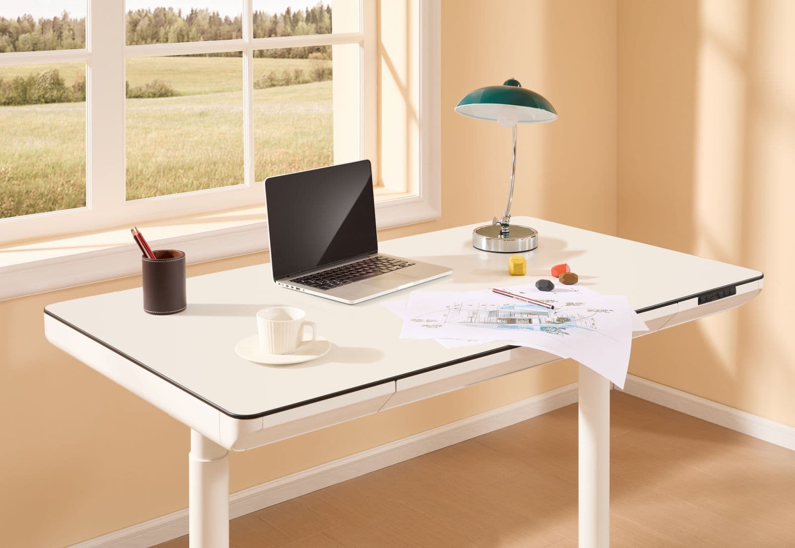 A bright home office with a height-adjustable desk, laptop and desk lamp beside a window