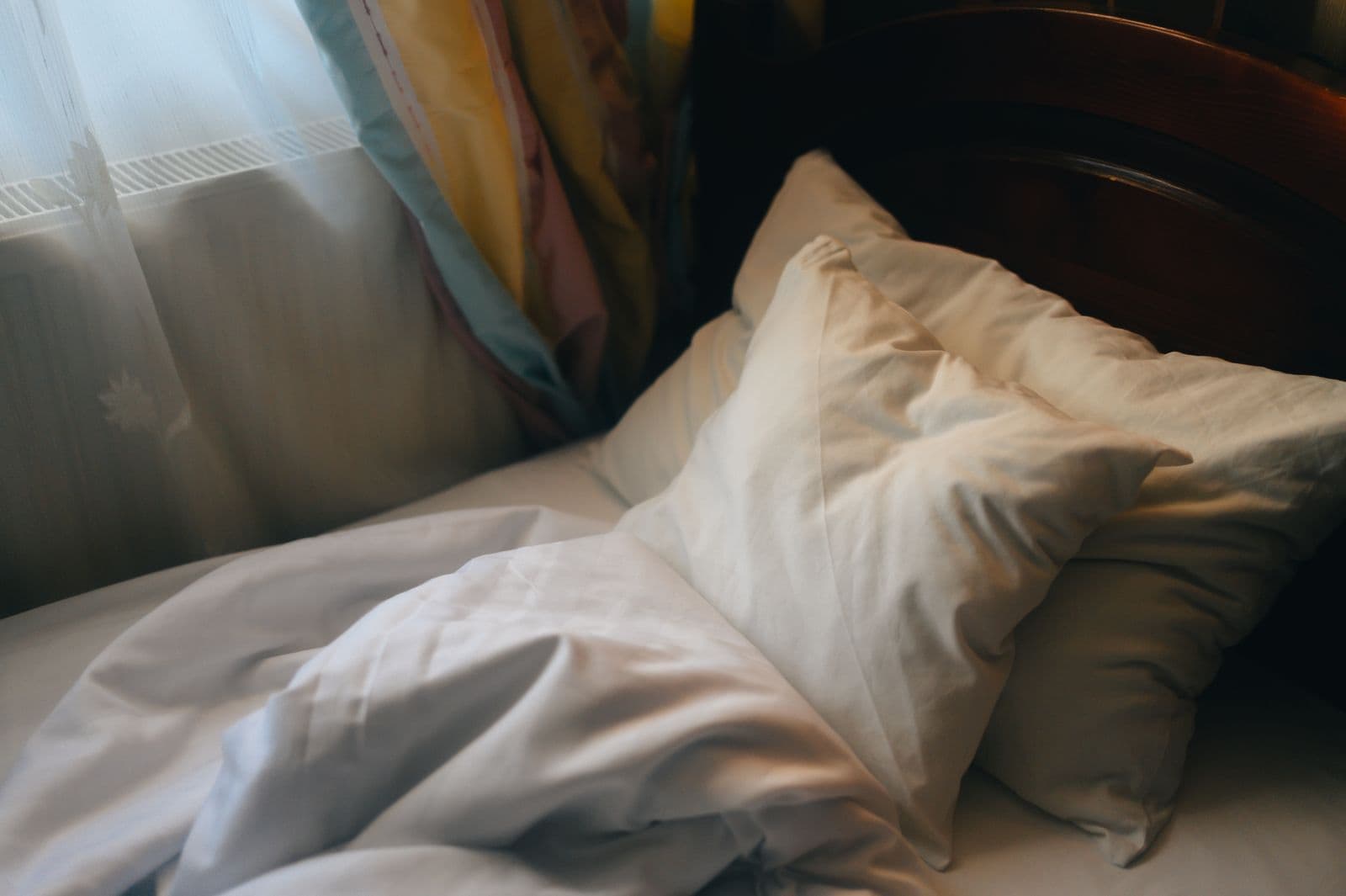 An empty bed with rumpled sheets in soft morning light
