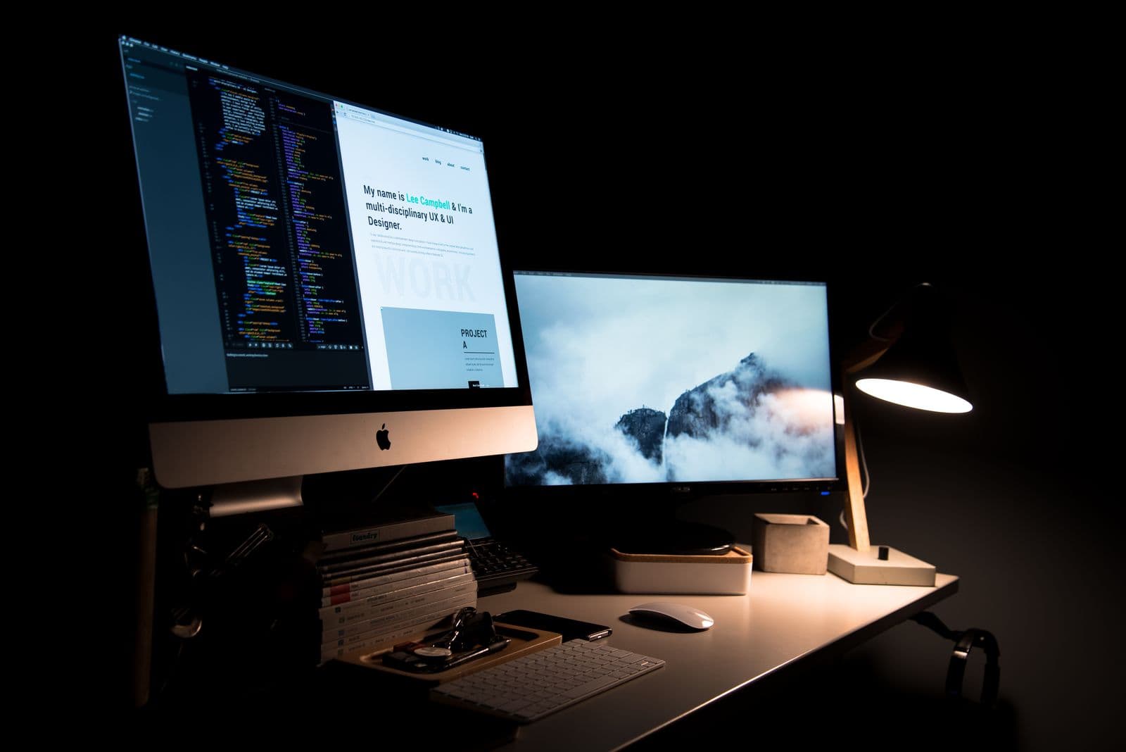A desk with dual monitors, a lamp and office supplies
