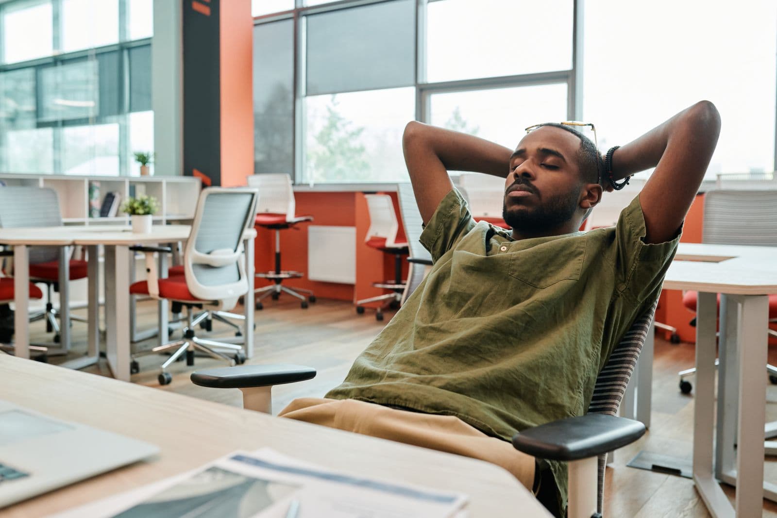 A man leaning back in an office chair in a modern workspace