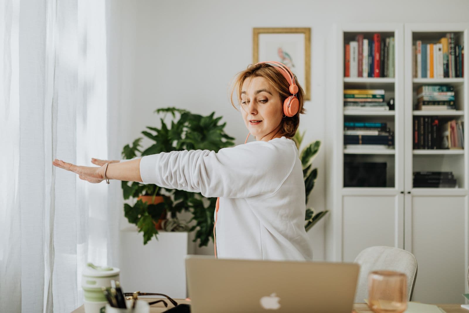 A person stretching their arms out beside a laptop in a home office