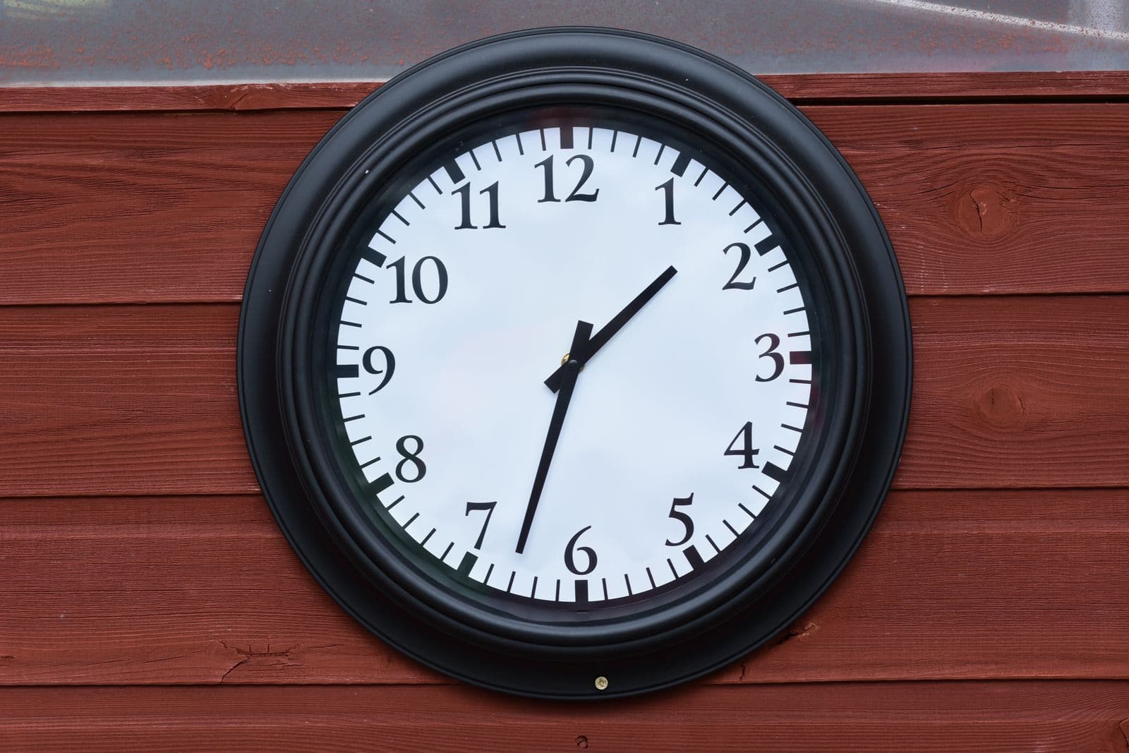 A round wall clock mounted on a wooden wall