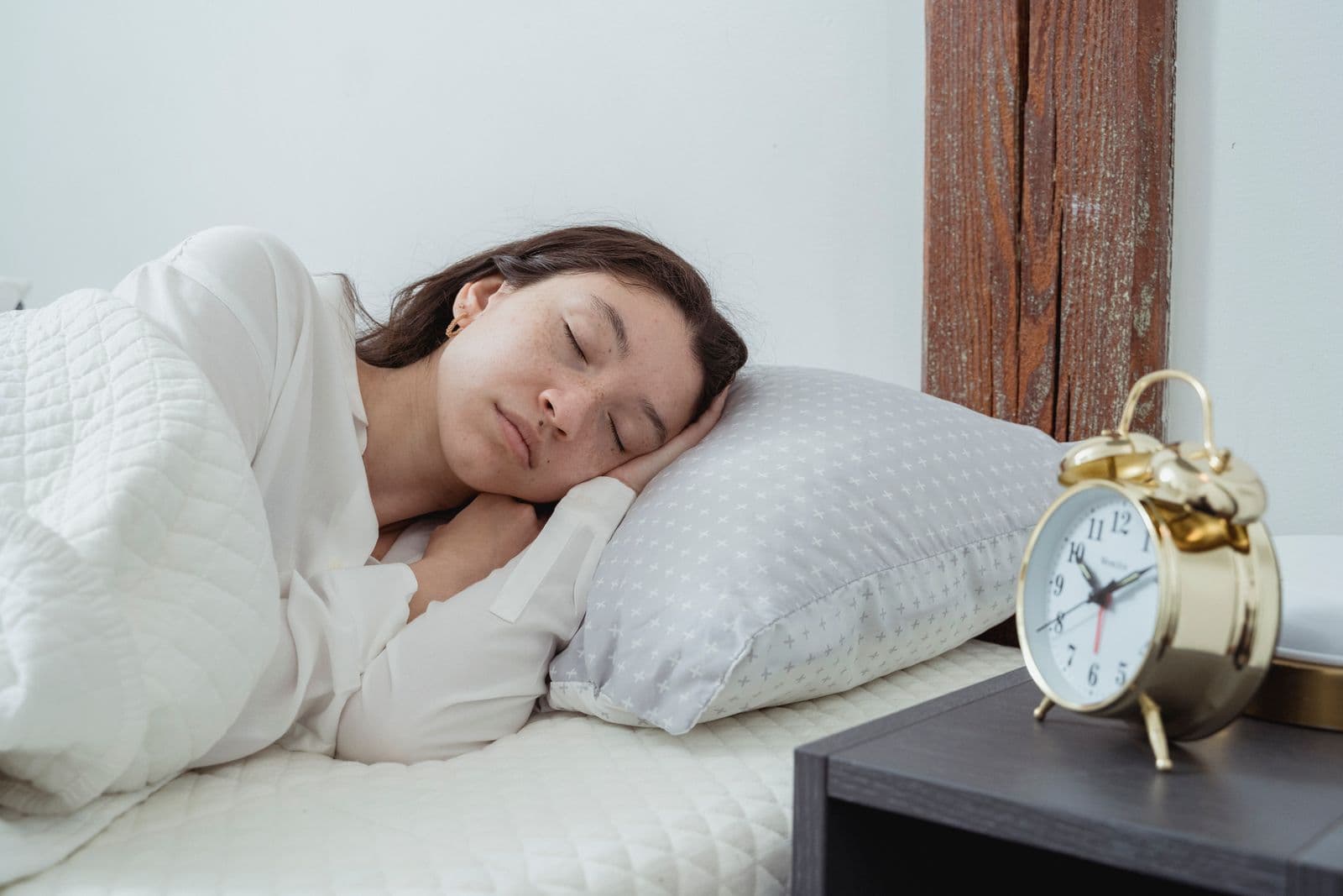 A person asleep on their side with their head resting on a white pillow