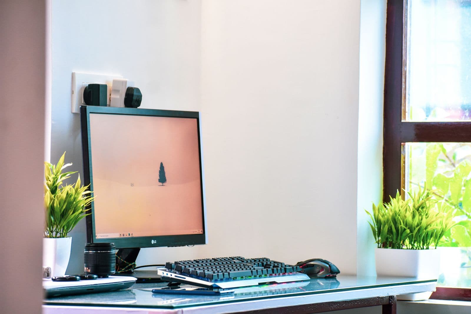 A computer and monitor on a desk beside a window in a bright home office
