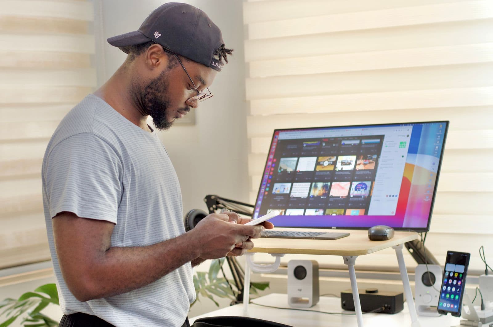 A person working while standing at a raised desk with a large monitor