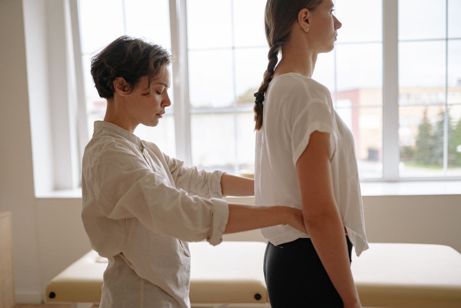 A therapist guiding a standing person's shoulder position