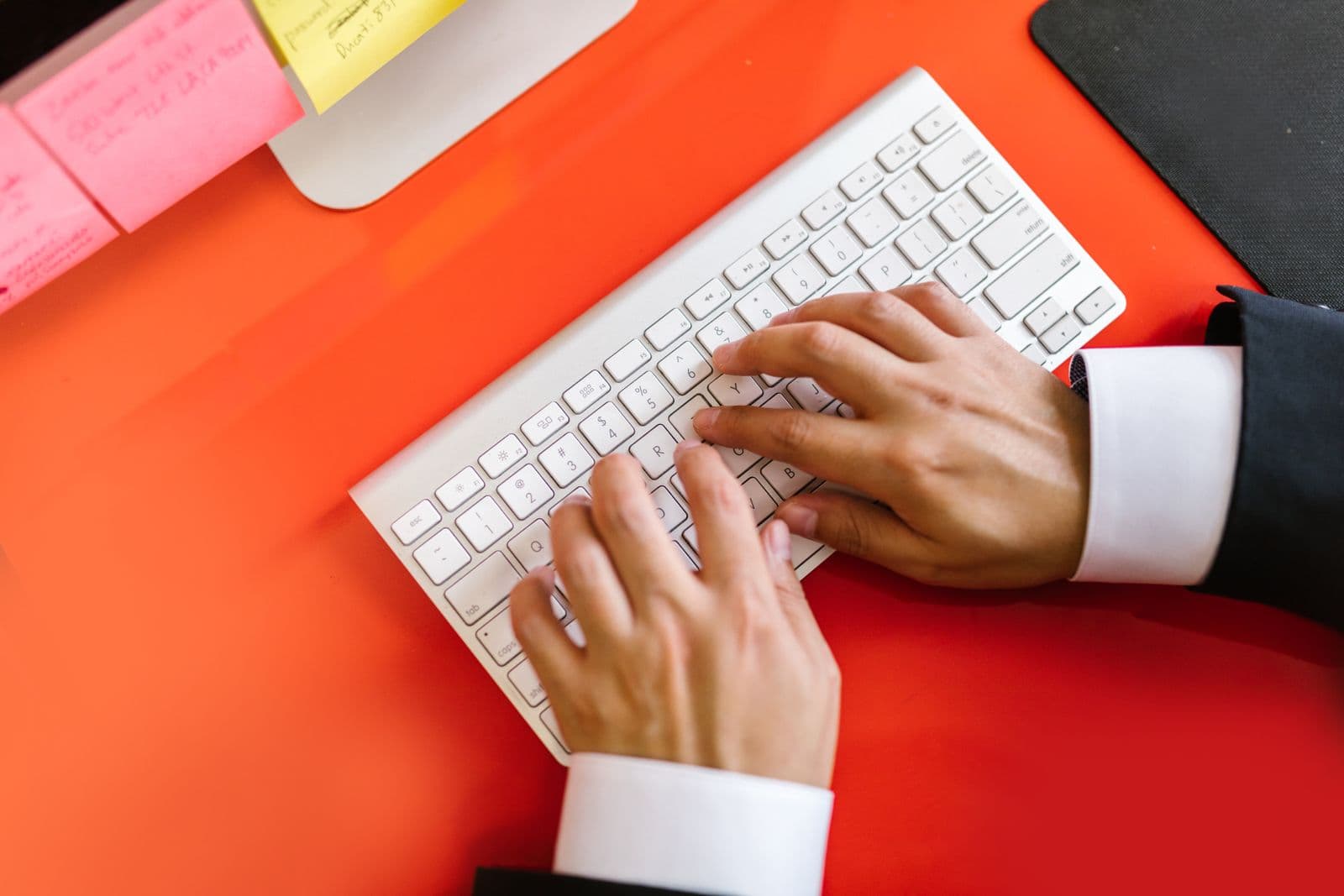 Close-up of hands typing on a keyboard on a desk